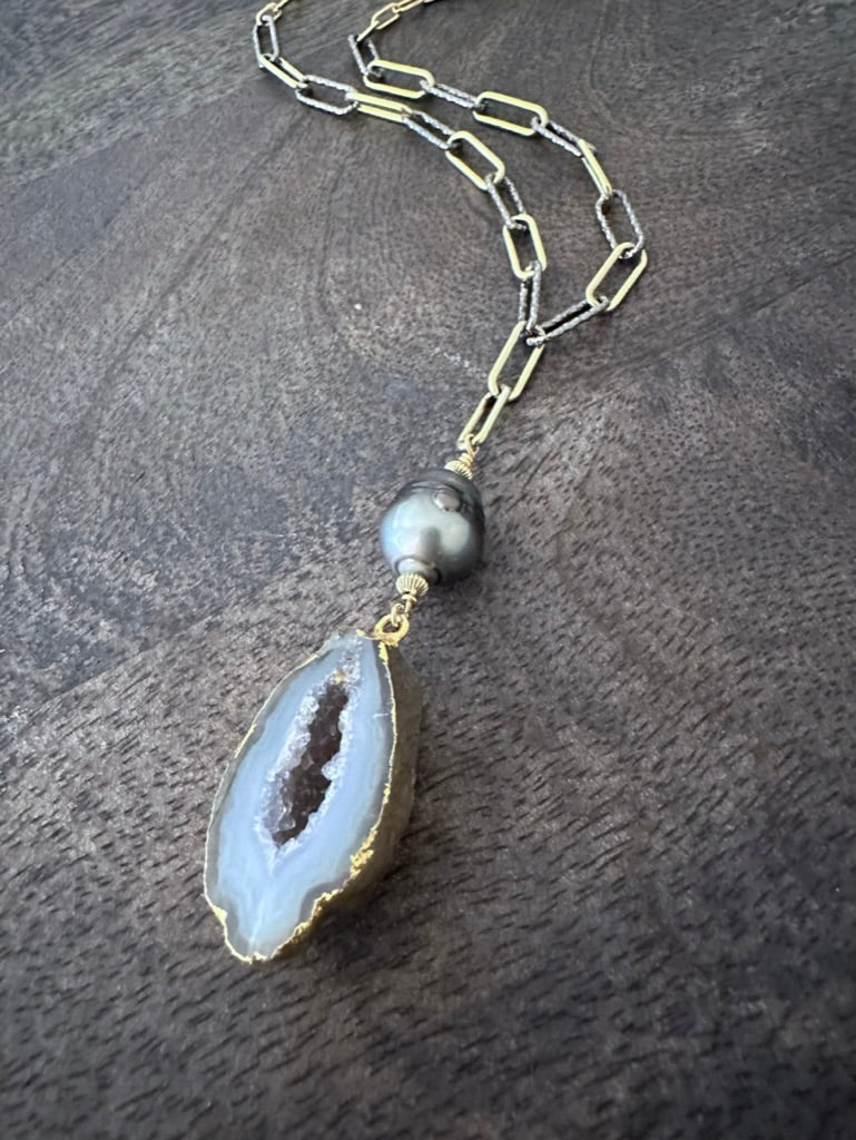 geode and black pearl on a gold and silver chain on a grey wooden background