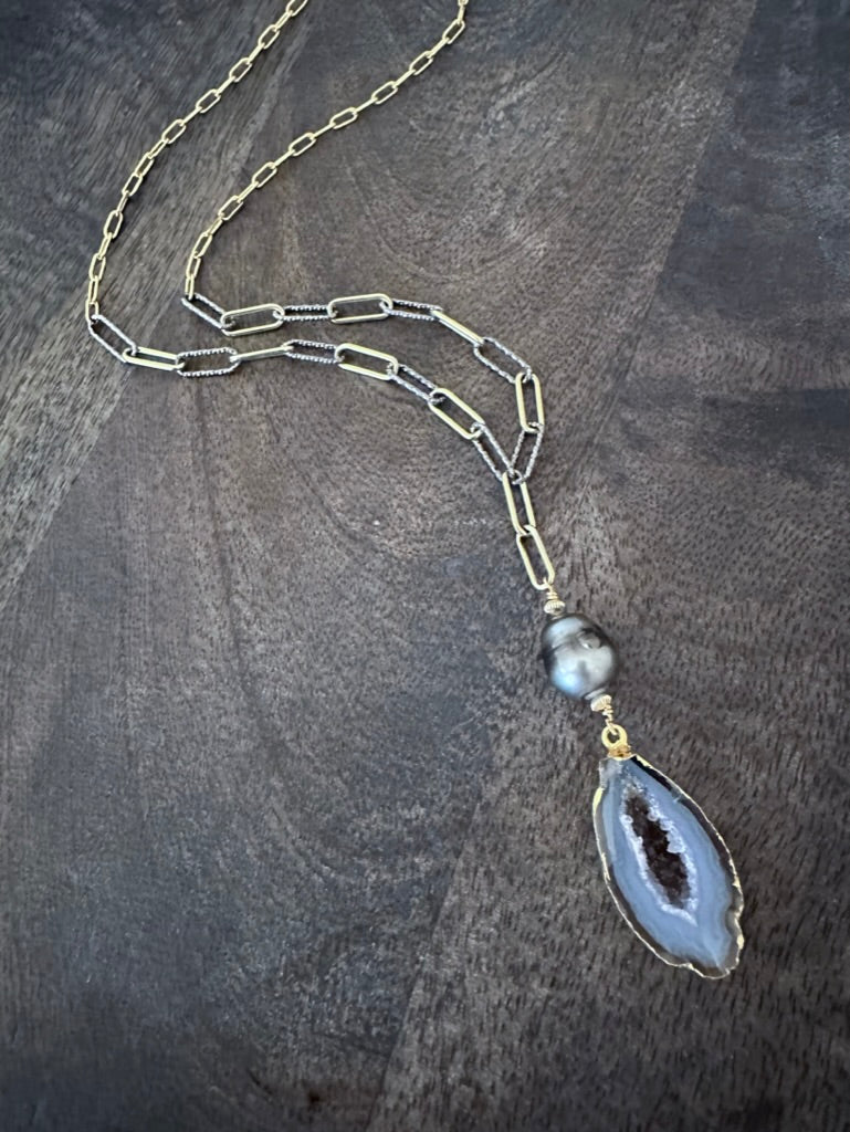 geode and black pearl on a gold and silver chain on a grey wooden background