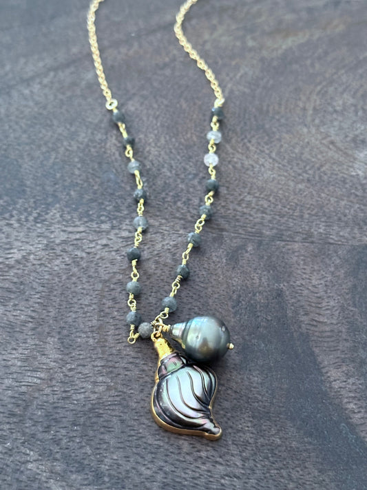 a necklace with grey beads wire wrapped in a rosary chain. there are two pendants n the center, one is a carved motherof pearl grey shell and the other is a tahitian pearl.