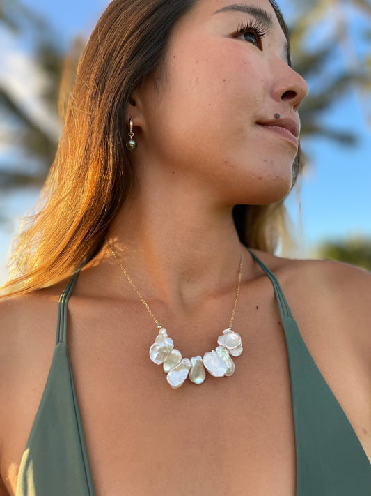 Pretty girl with a green bikini on wearing a necklace with a bar of flat white pearls