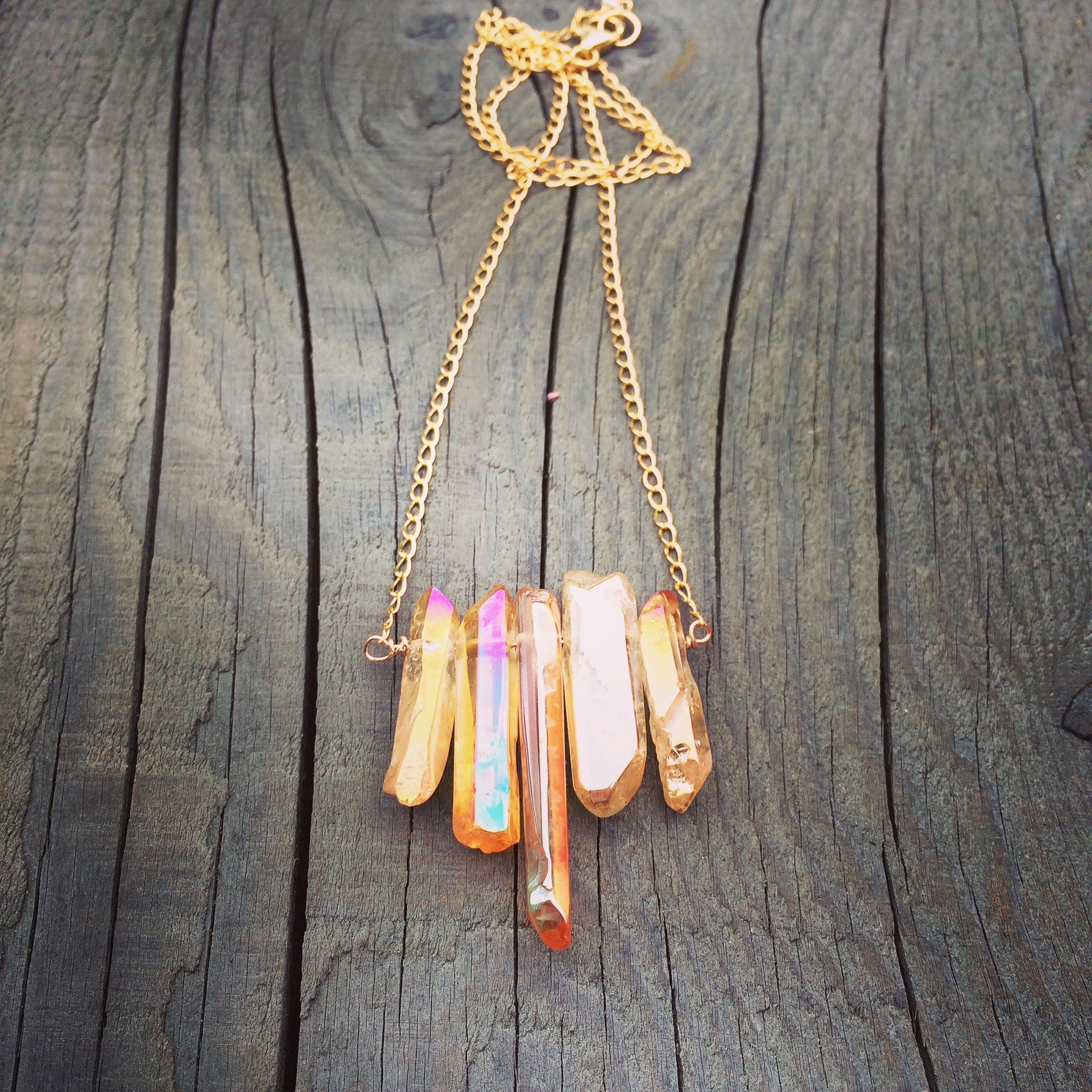 Five orangey peach crystals in a row on a chain on a wooden background.