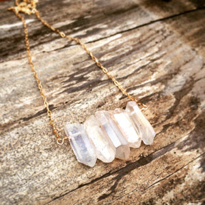 Five clear crystals in a row on a gold chain on a wooden background