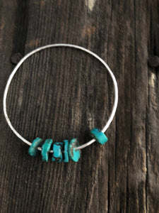 6 pieces of turquoise on a silver bangle on a wooden background