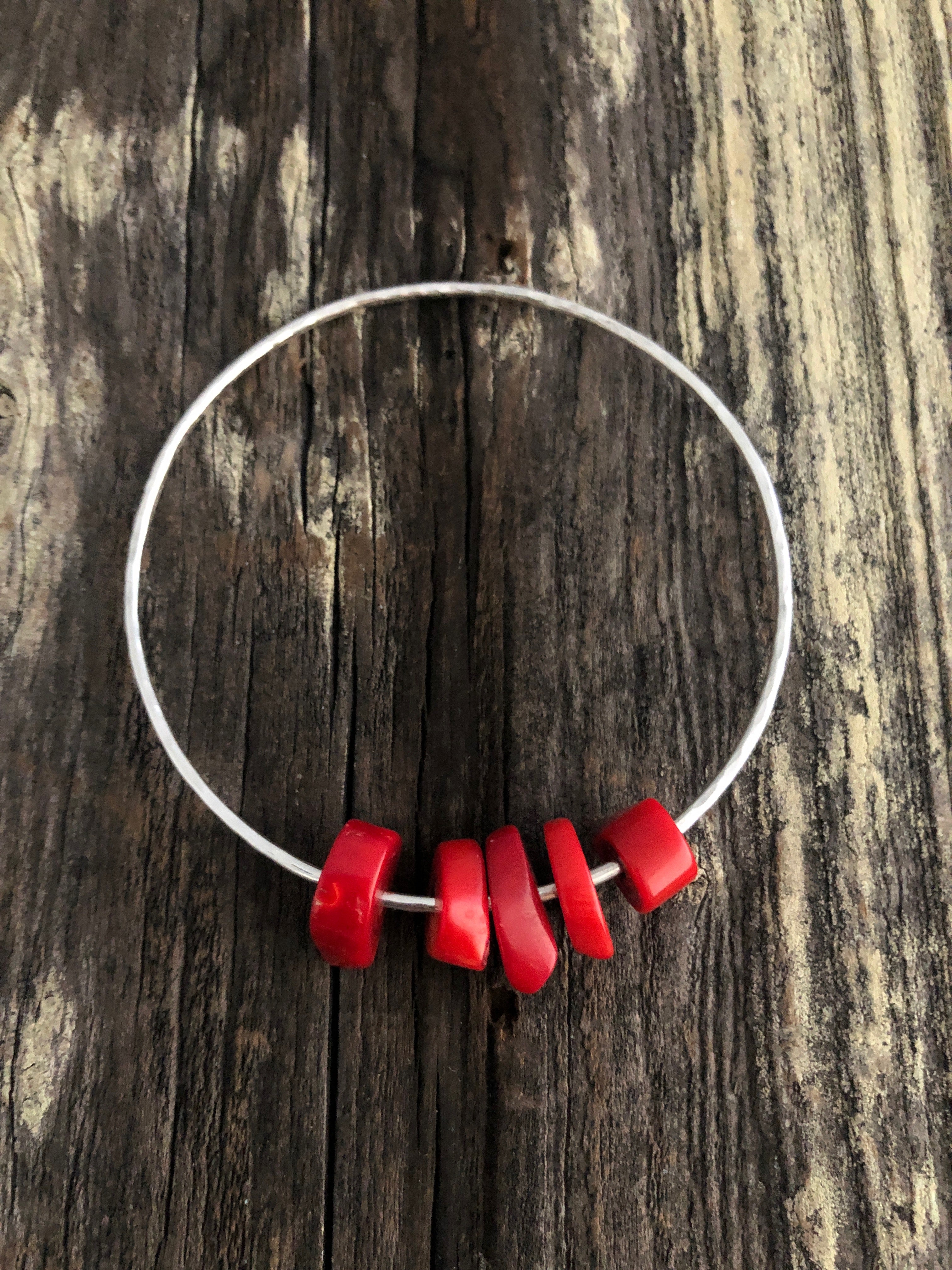 5 pieces of coral on a silver bangle on a wooden background