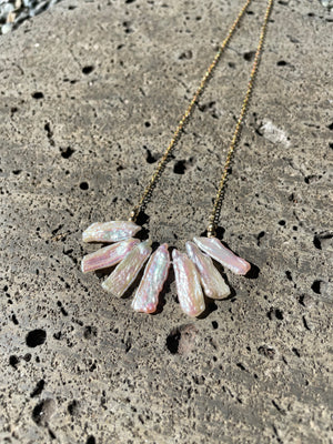 A bar of long grey pearls on gold necklace on a grey stone background