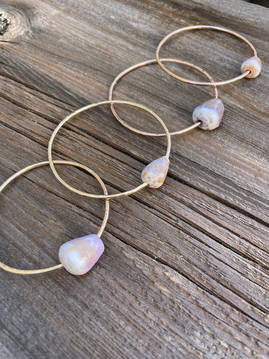 Four gold bangles with cone shaped shells on a wooden background 