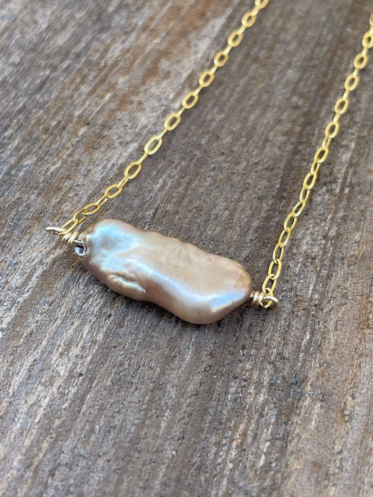 large golden pearl wire wrapped on a gold chain on a wooden background