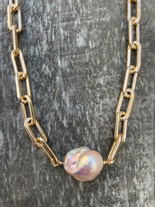 Extra large gold linked chain with a large luminescent pink fireball pearl in the center. 